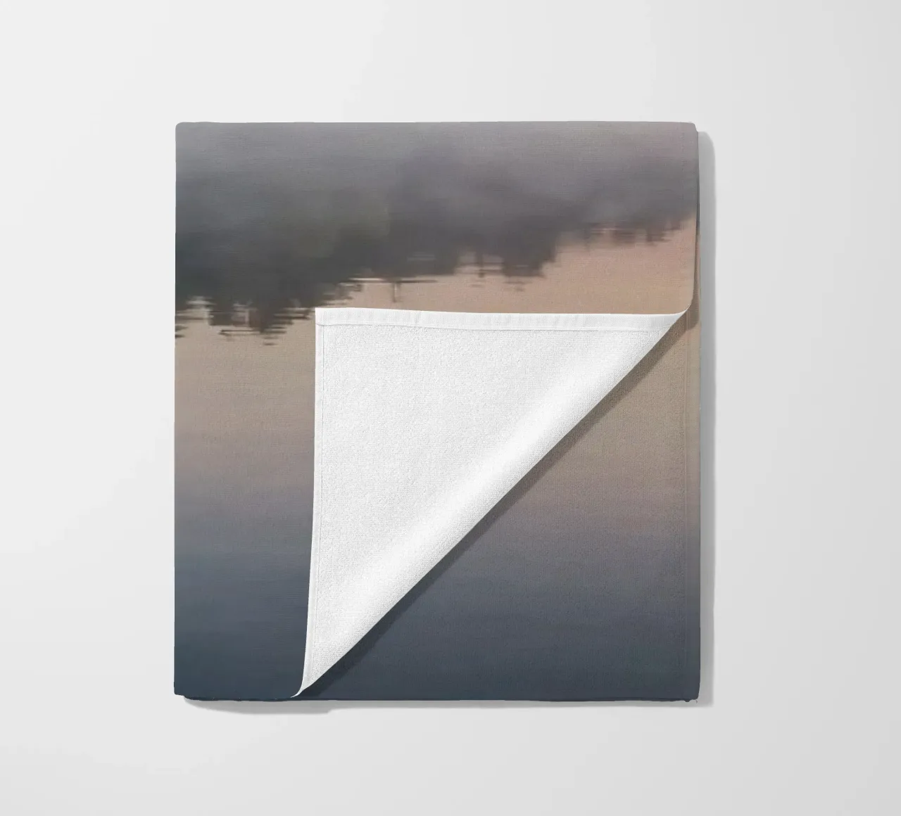 mist rises over a tranquil lake surrounded by lush trees beach towel by DesignDoodle