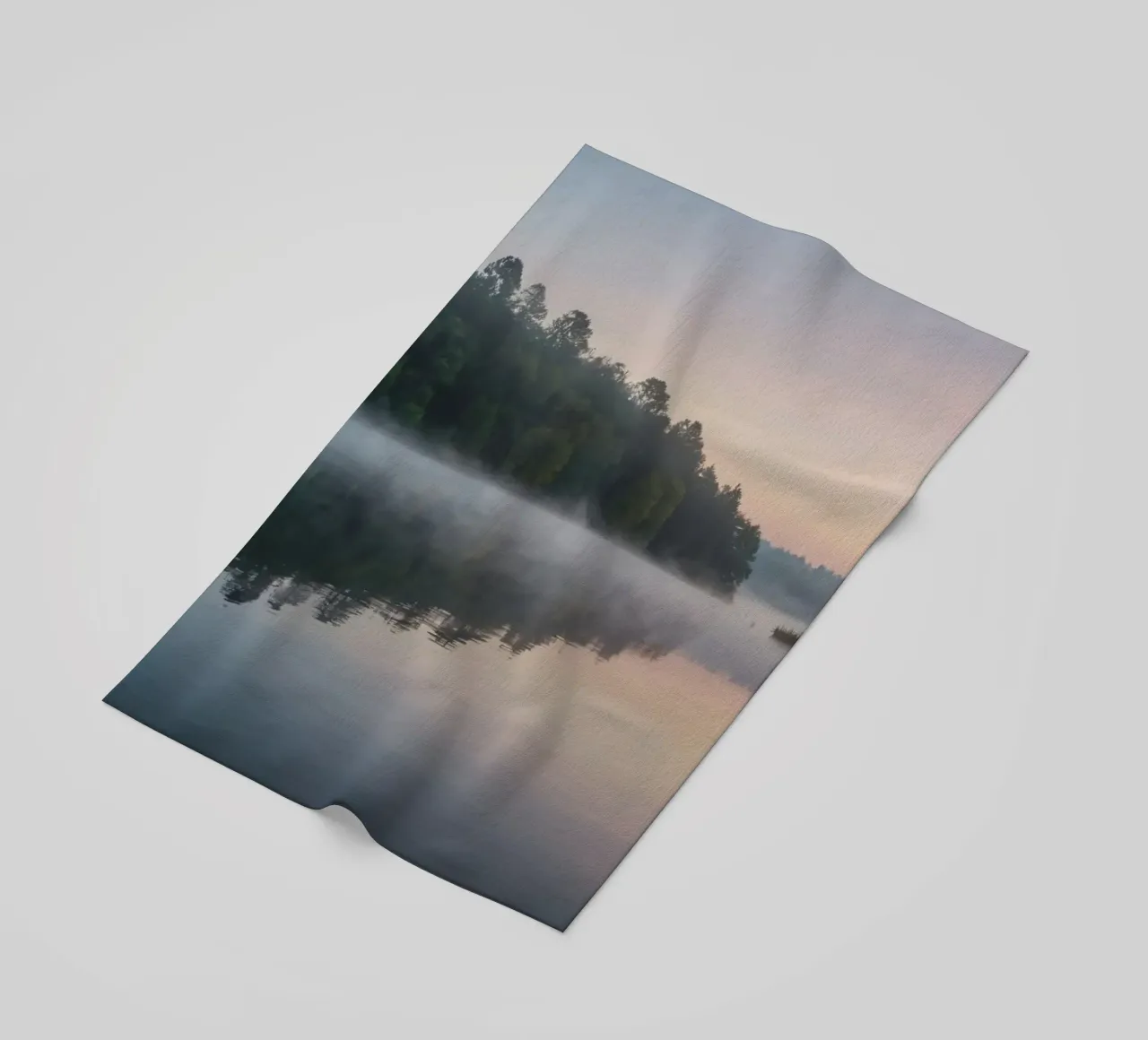 mist rises over a tranquil lake surrounded by lush trees beach towel by DesignDoodle