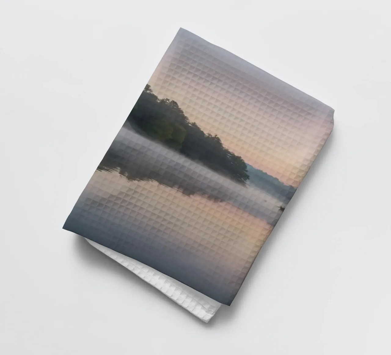 mist rises over a tranquil lake surrounded by lush trees tea towel by DesignDoodle