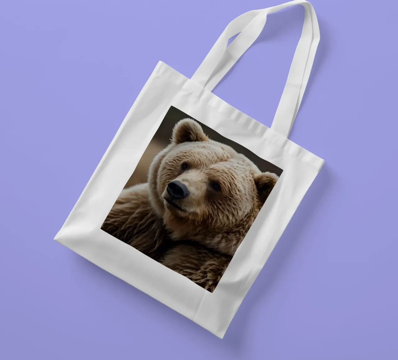 Vue rapprochée d'un ours brun se reposant dans un champ herbeux. tote bag de DesignDoodle