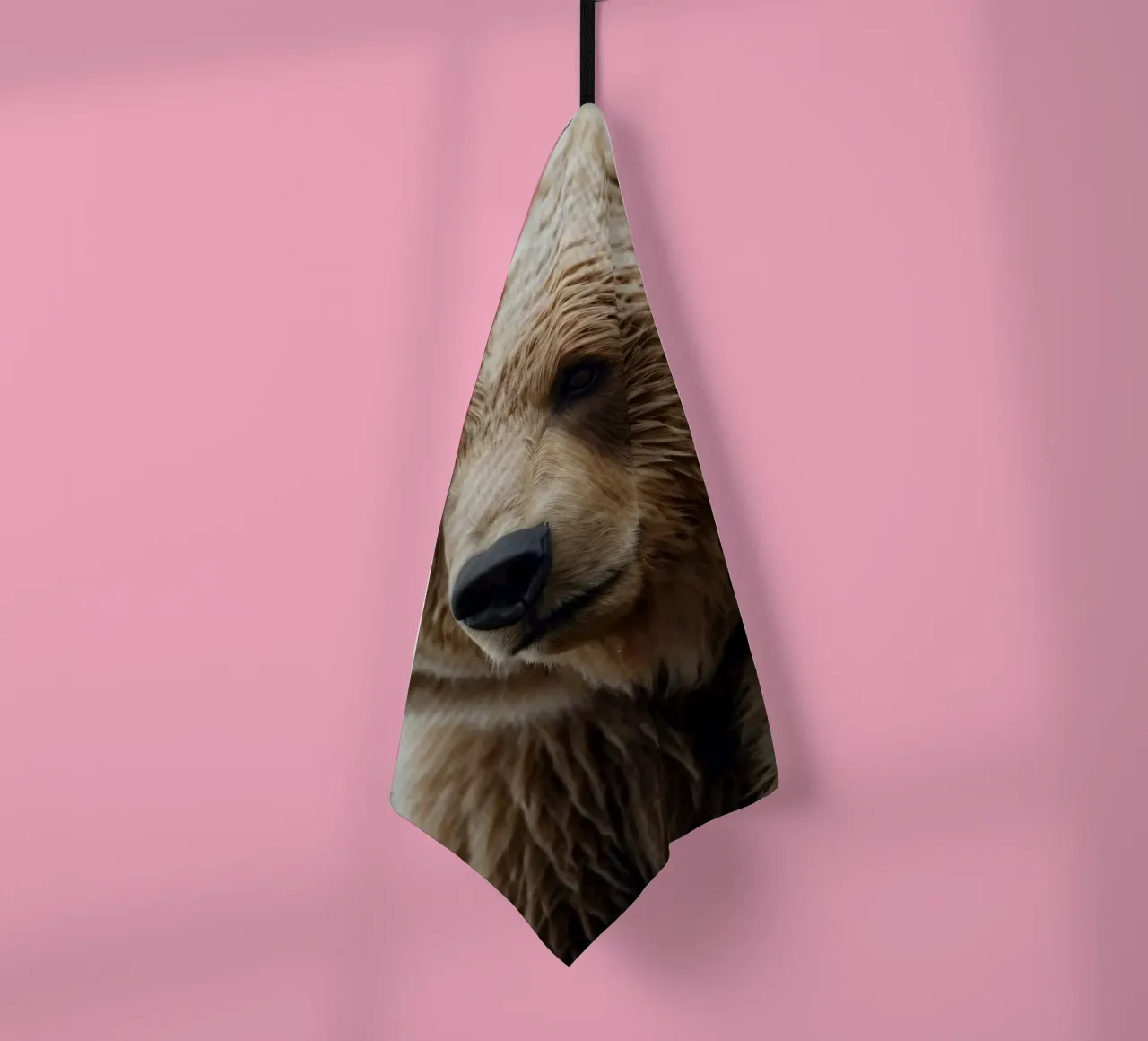 A close-up view of a brown bear resting in a grassy field tea towel by DesignDoodle