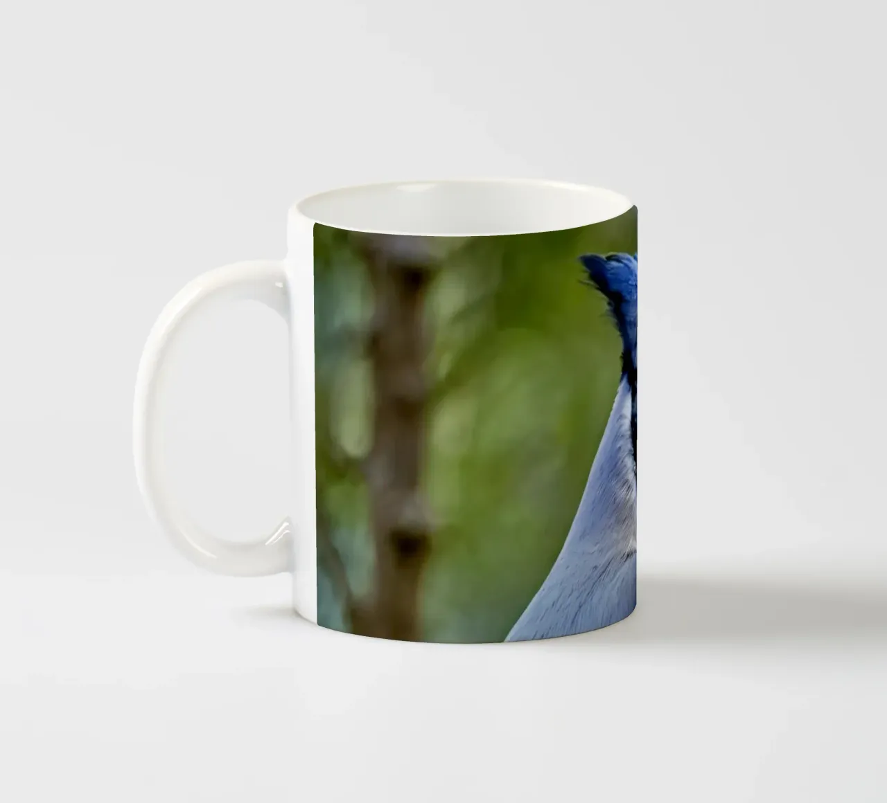 Una ghiandaia azzurra appollaiata sul ramo di un albero in una foresta verdeggiante tazza in ceramica da DesignDoodle