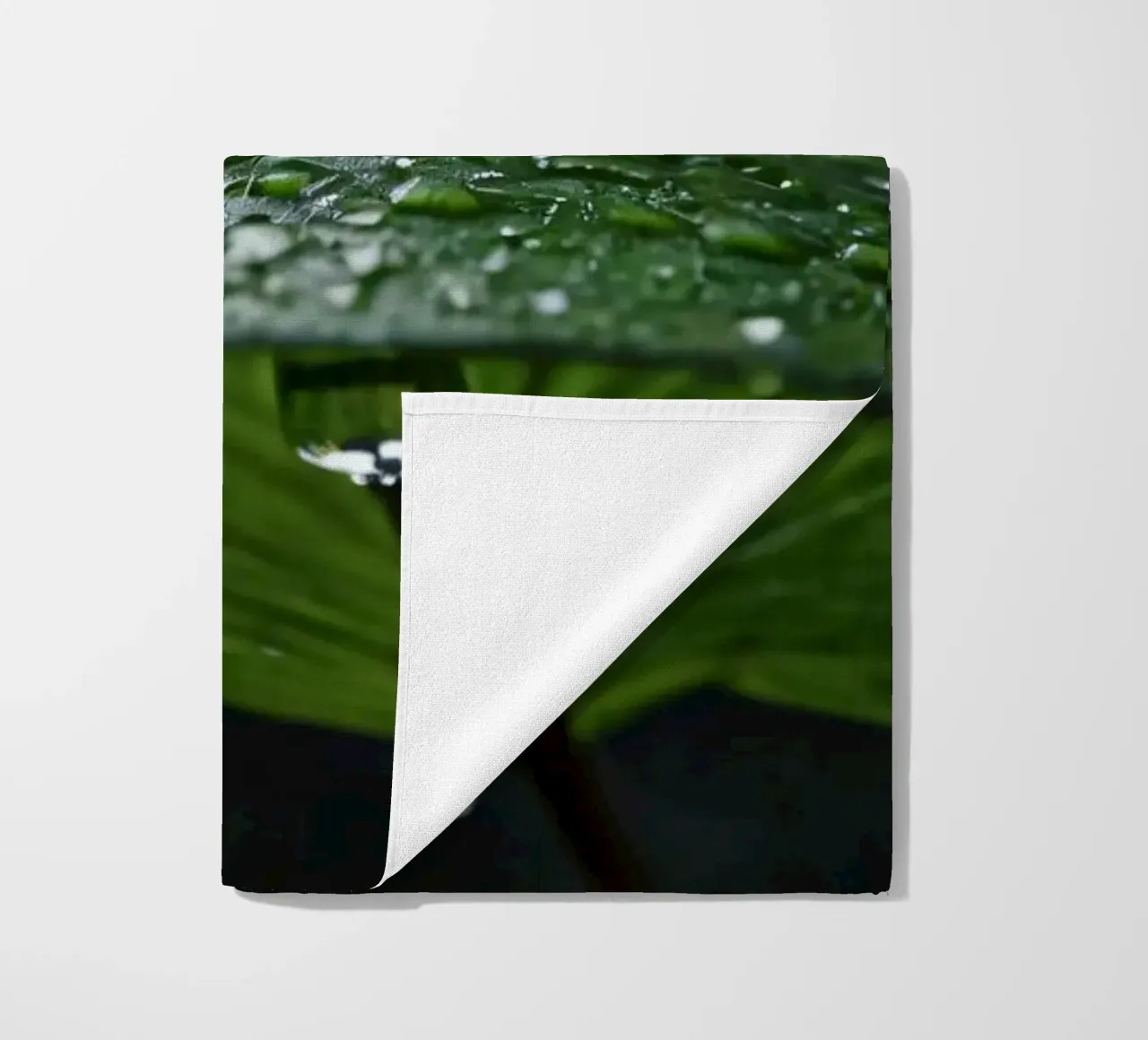 Raindrops collect on vibrant green leaves in a lush forest beach towel by DesignDoodle