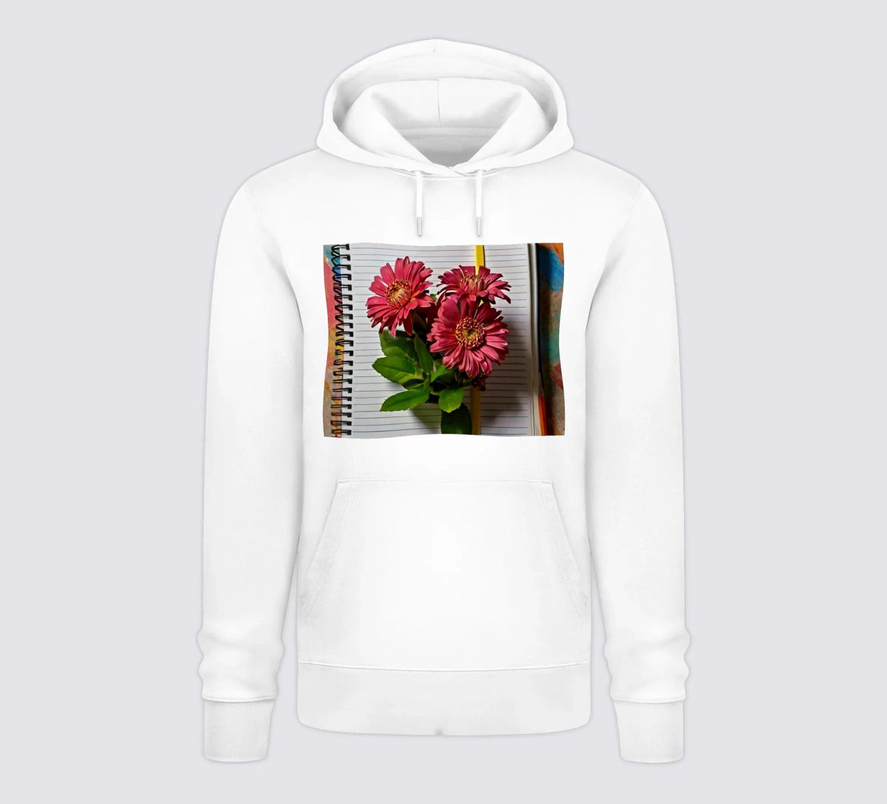 Un taccuino vivace con fiori rosa appoggiati in cima, che mette in mostra felpa con cappuccio da DesignDoodle