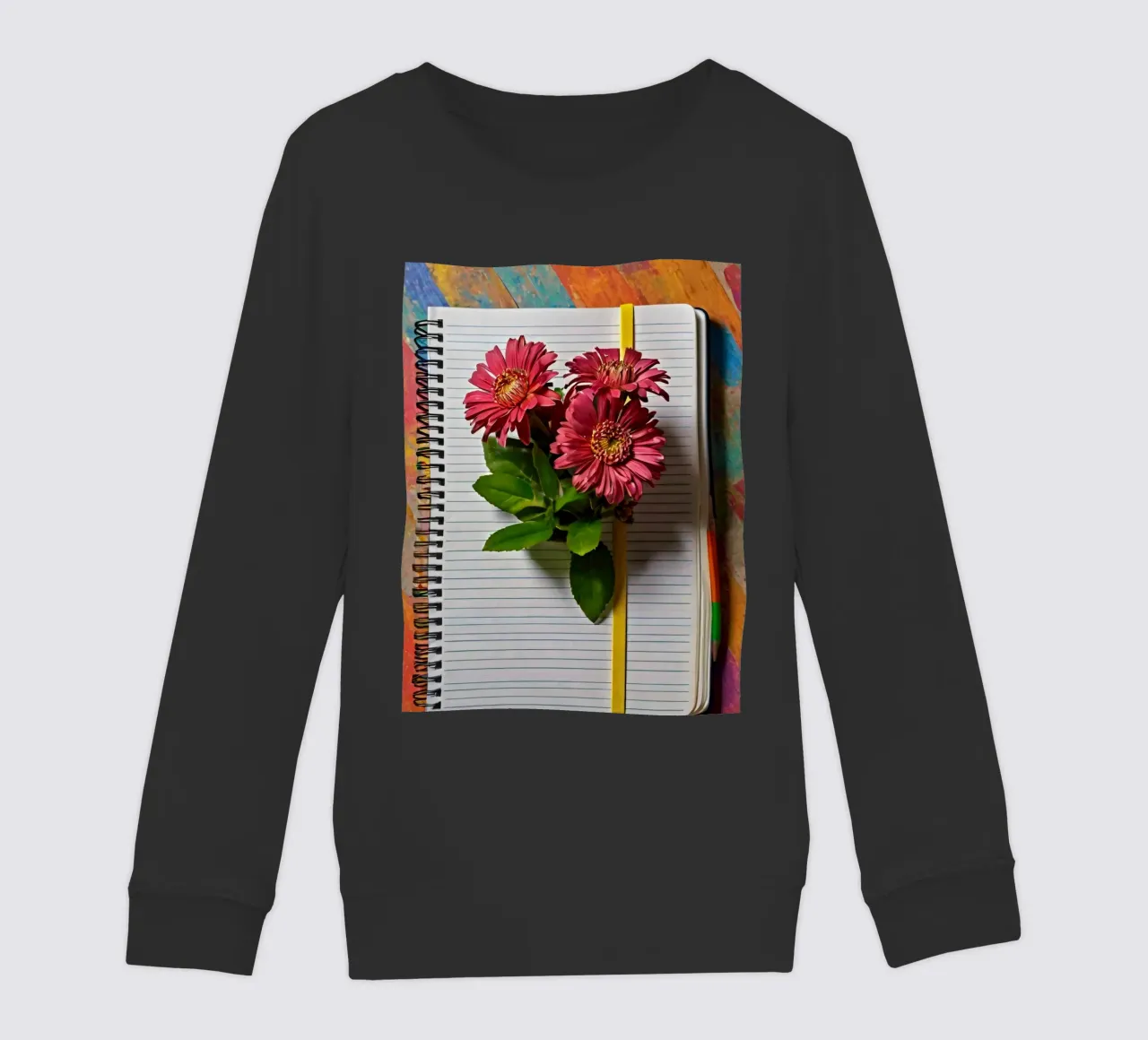 Un taccuino vivace con fiori rosa appoggiati in cima, che mette in mostra felpa bambino da DesignDoodle
