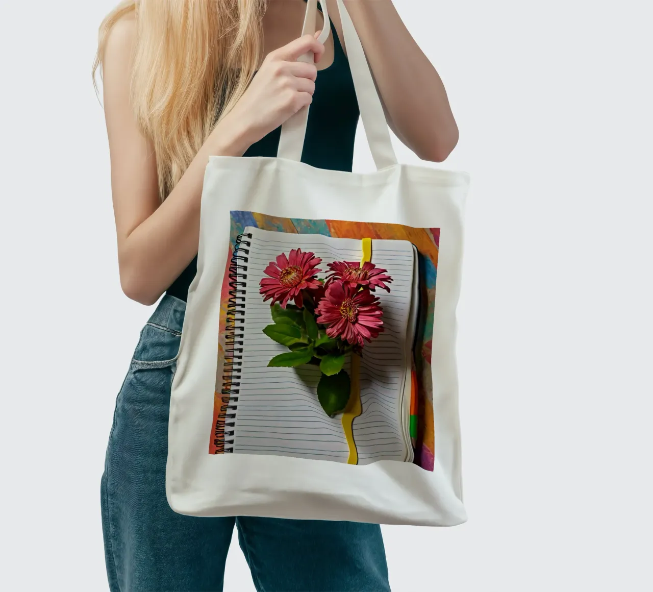 Un taccuino vivace con fiori rosa appoggiati in cima, che mette in mostra borsa in juta da DesignDoodle