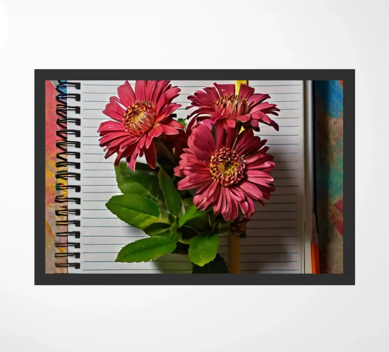 Un taccuino vivace con fiori rosa appoggiati in cima, che mette in mostra zerbino da DesignDoodle