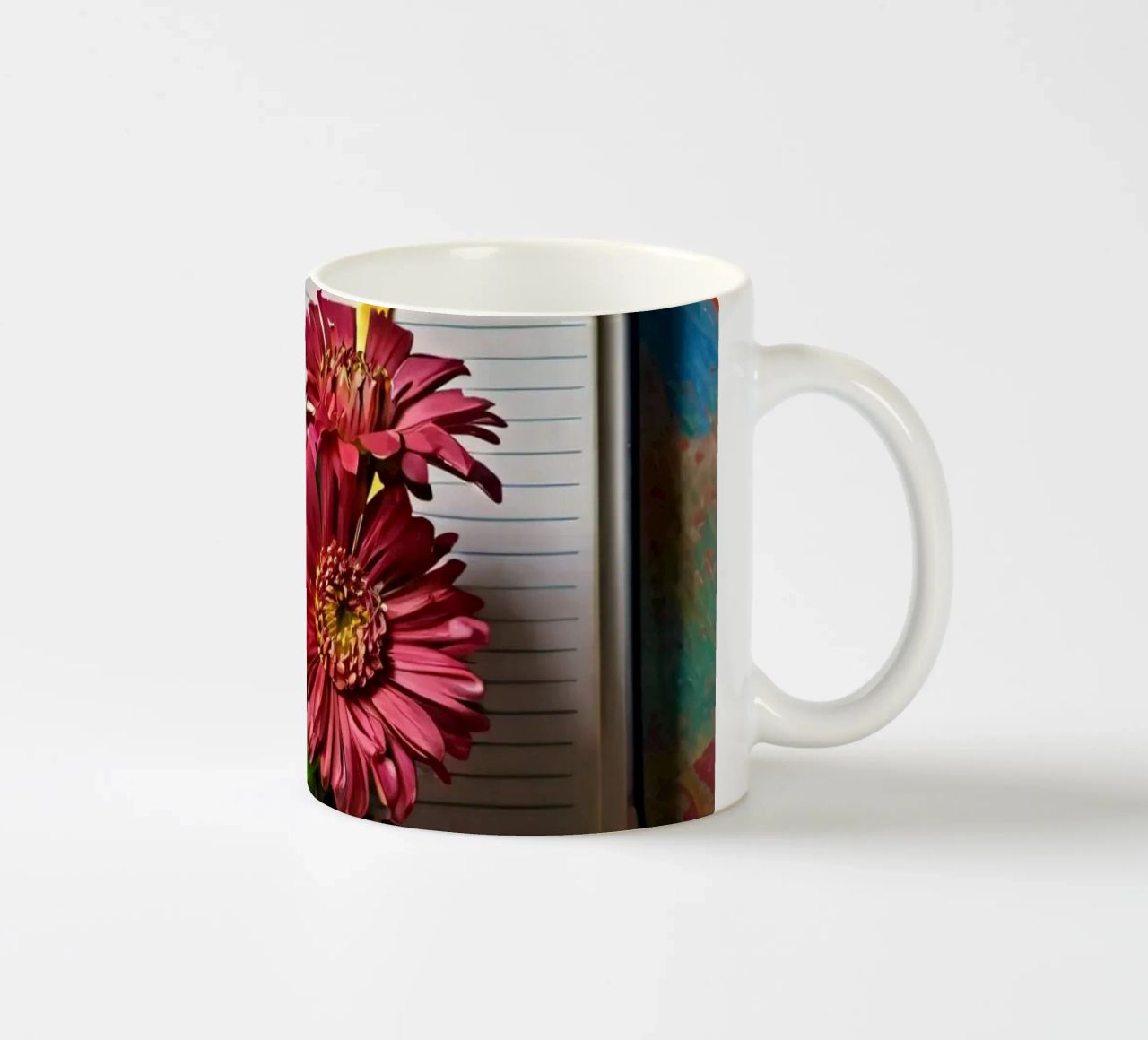 Un taccuino vivace con fiori rosa appoggiati in cima, che mette in mostra tazza in ceramica da DesignDoodle