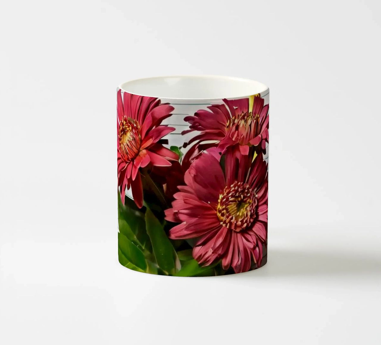 Un taccuino vivace con fiori rosa appoggiati in cima, che mette in mostra tazza in ceramica da DesignDoodle
