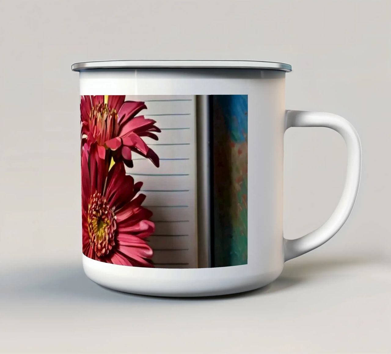 Un taccuino vivace con fiori rosa appoggiati in cima, che mette in mostra tazza in smalto da DesignDoodle