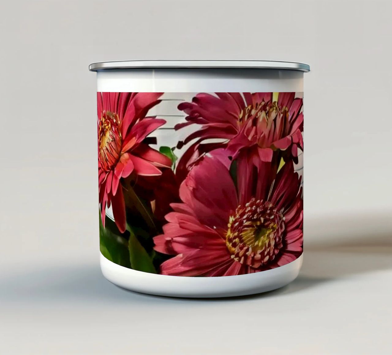 Un taccuino vivace con fiori rosa appoggiati in cima, che mette in mostra tazza in smalto da DesignDoodle