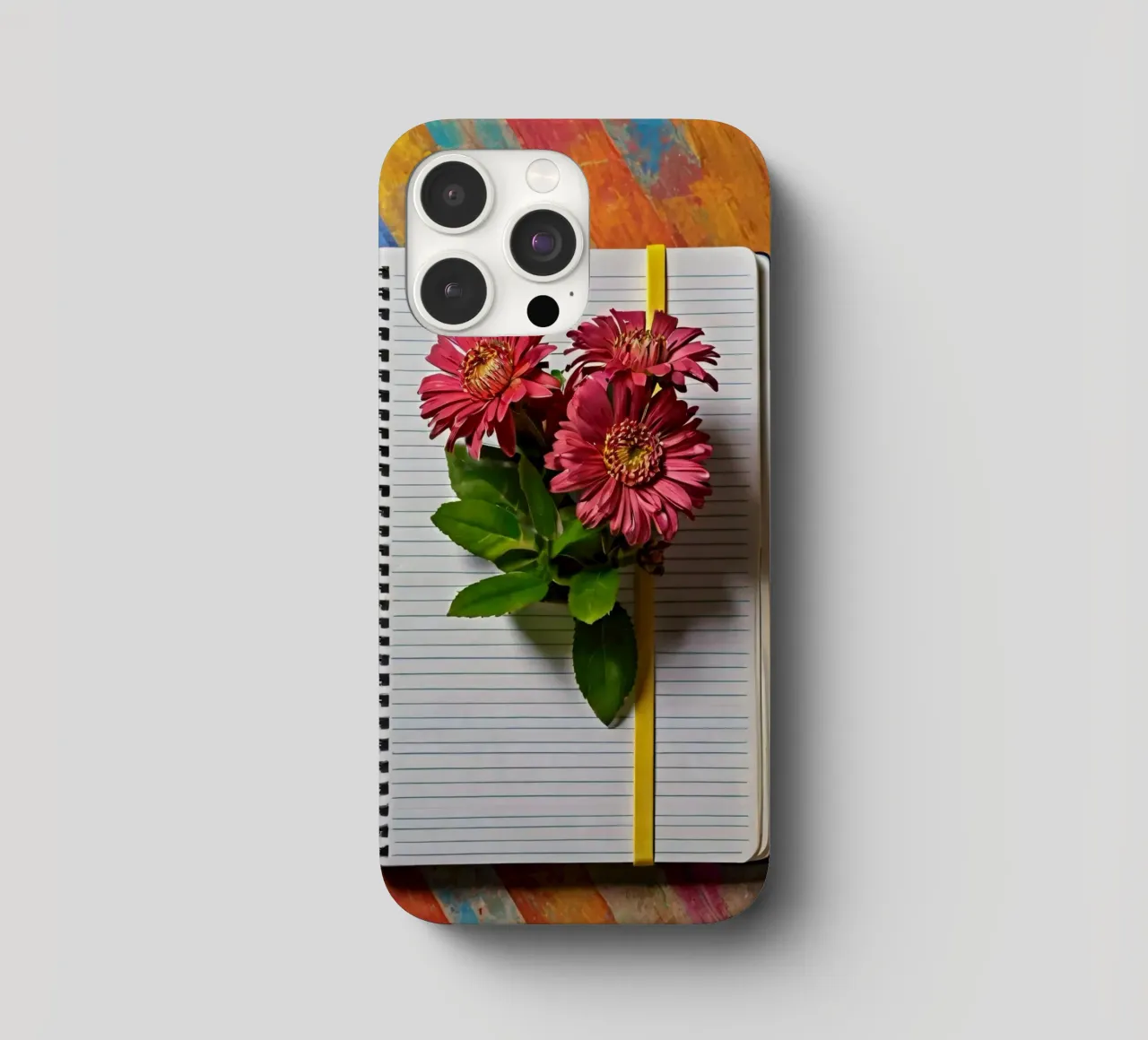 Un taccuino vivace con fiori rosa appoggiati in cima, che mette in mostra cover iphone da DesignDoodle
