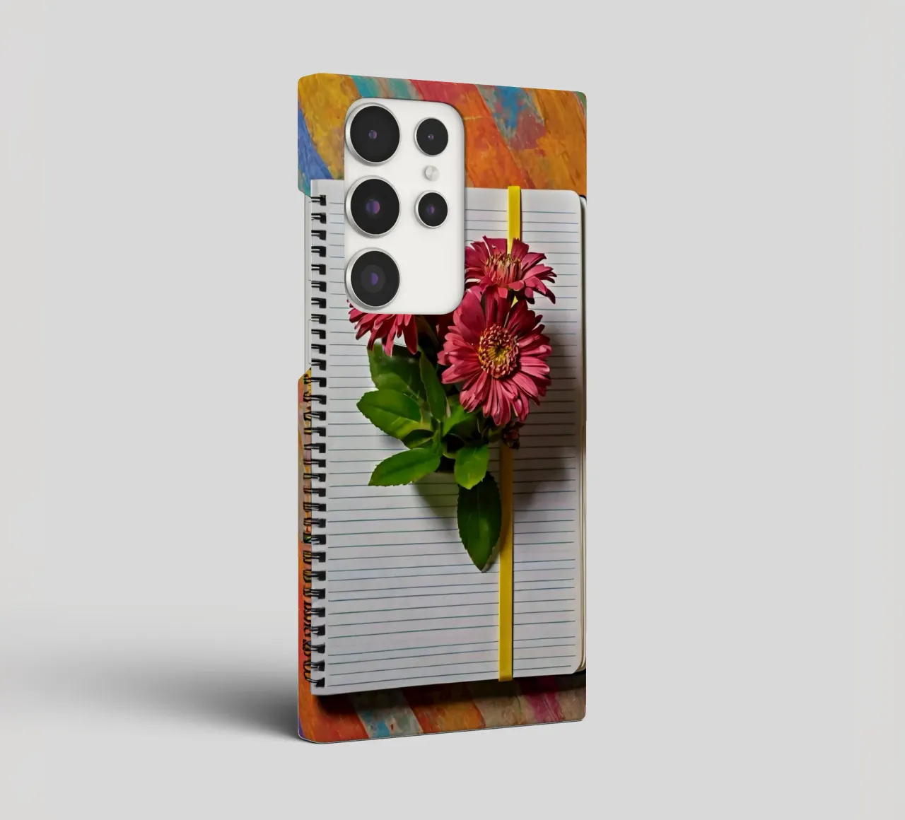 Un taccuino vivace con fiori rosa appoggiati in cima, che mette in mostra cover samsung da DesignDoodle