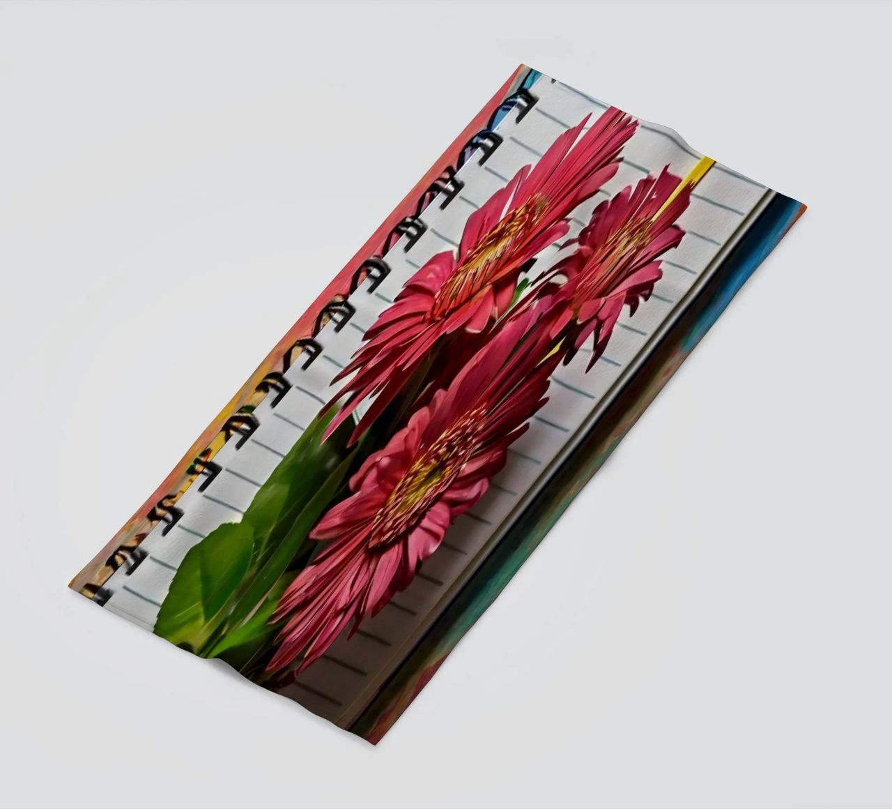 Un taccuino vivace con fiori rosa appoggiati in cima, che mette in mostra telo mare da DesignDoodle