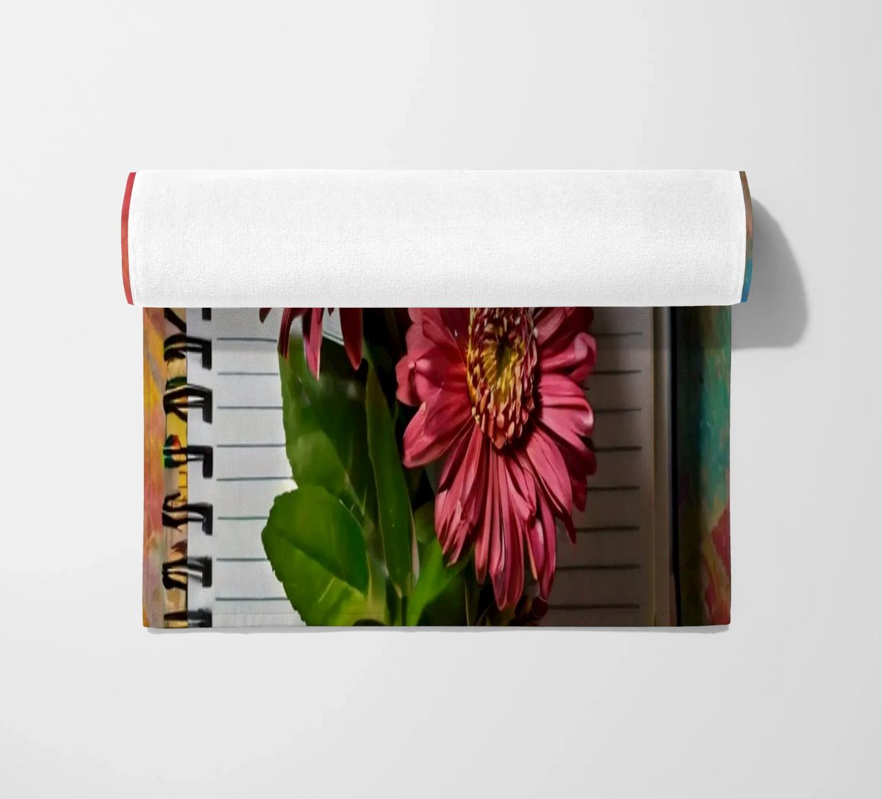 Un taccuino vivace con fiori rosa appoggiati in cima, che mette in mostra telo mare da DesignDoodle