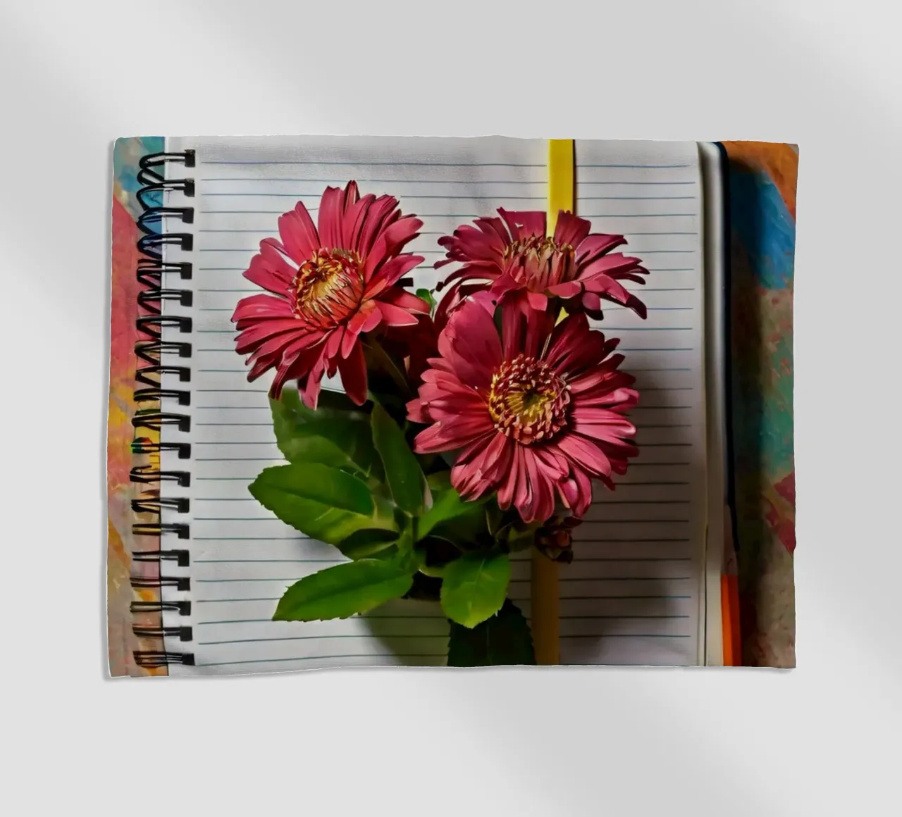 Ein leuchtendes Notizbuch mit rosafarbenen Blumen auf dem Kopf, die Strandtuch von DesignDoodle