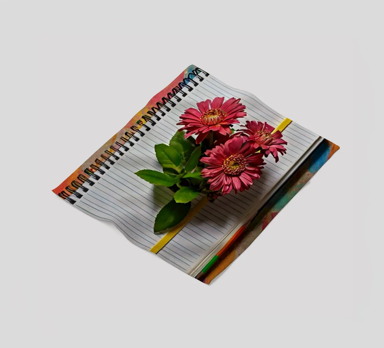 Un taccuino vivace con fiori rosa appoggiati in cima, che mette in mostra coperta in pile da DesignDoodle