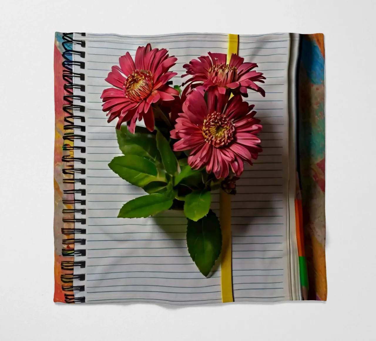 Un taccuino vivace con fiori rosa appoggiati in cima, che mette in mostra coperta in pile da DesignDoodle