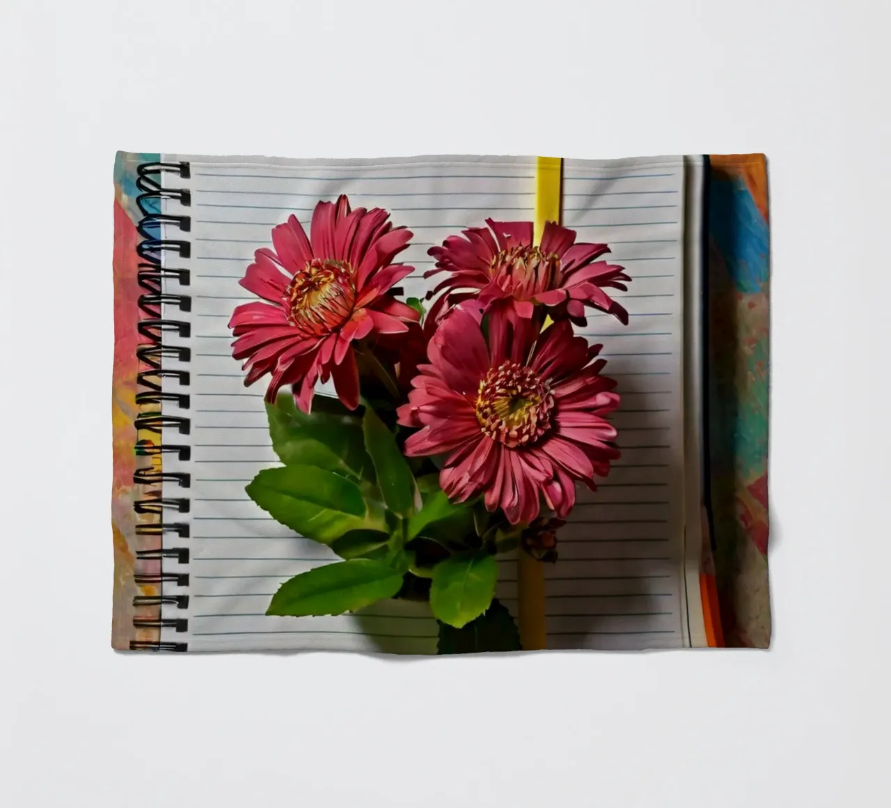 Un taccuino vivace con fiori rosa appoggiati in cima, che mette in mostra coperta in pile da DesignDoodle