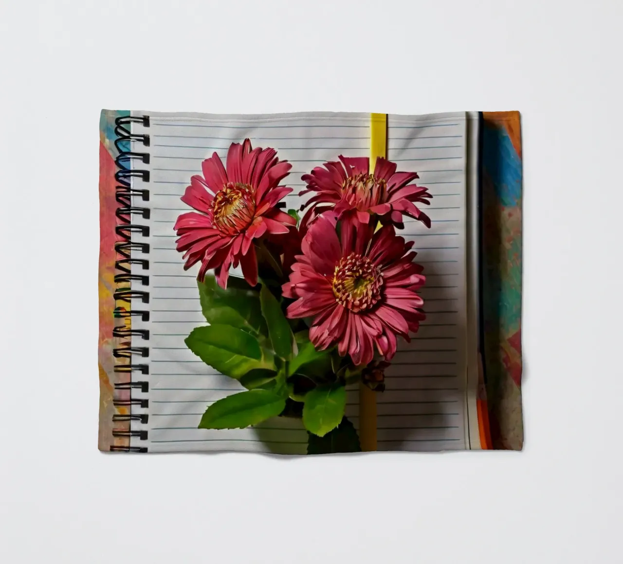 Un taccuino vivace con fiori rosa appoggiati in cima, che mette in mostra coperta in pile da DesignDoodle