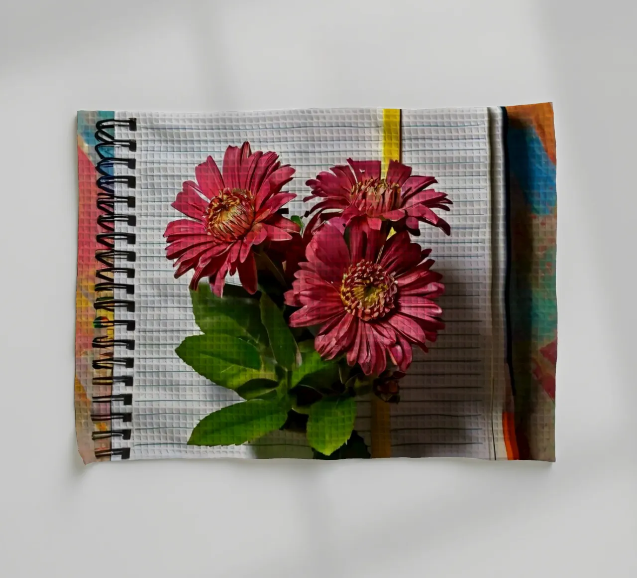 Un taccuino vivace con fiori rosa appoggiati in cima, che mette in mostra canovaccio da cucina da DesignDoodle