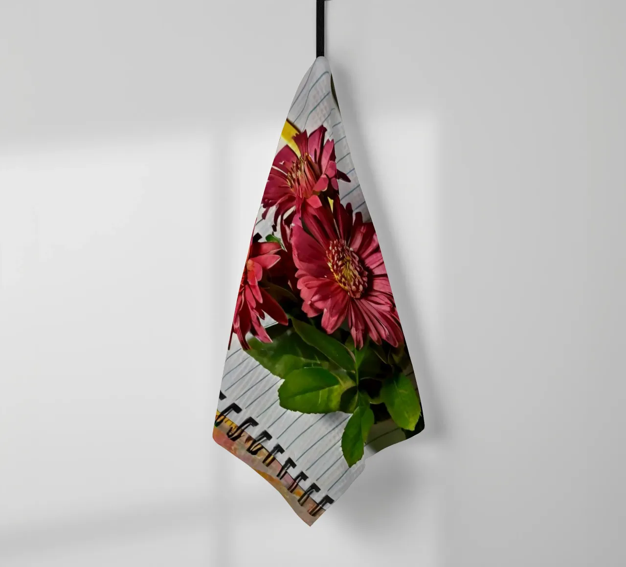 Un taccuino vivace con fiori rosa appoggiati in cima, che mette in mostra canovaccio da cucina da DesignDoodle