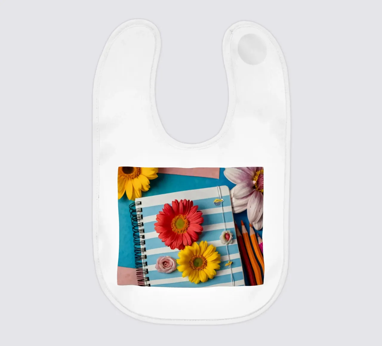 Colorful notebook adorned with flowers surrounded by pencils baby bib by DesignDoodle