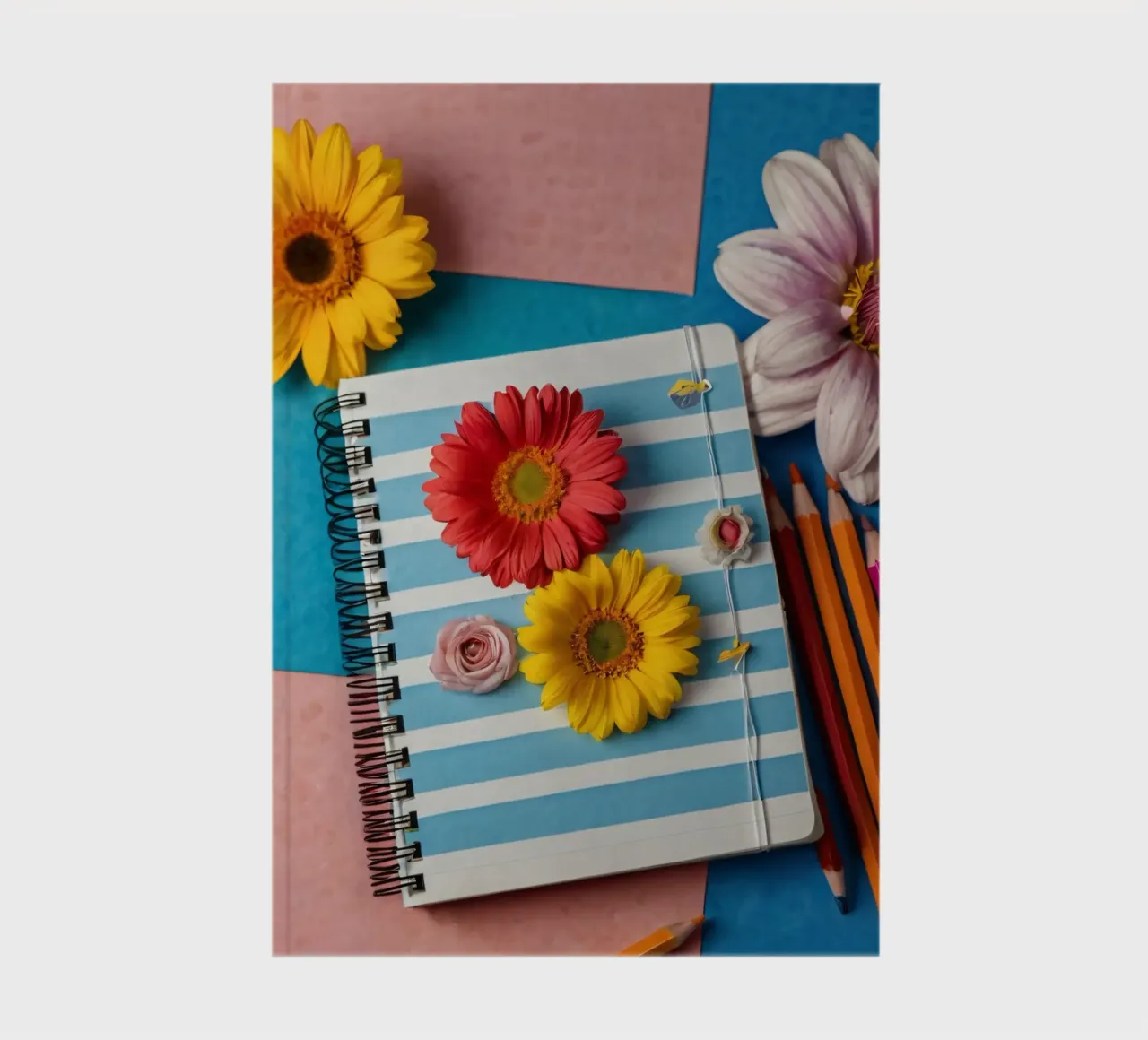 Taccuino colorato ornato di fiori e circondato da matite diario da DesignDoodle