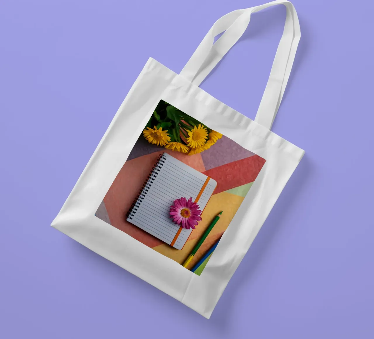Uno spazio di lavoro colorato con un taccuino con un fiore borsa in juta da DesignDoodle