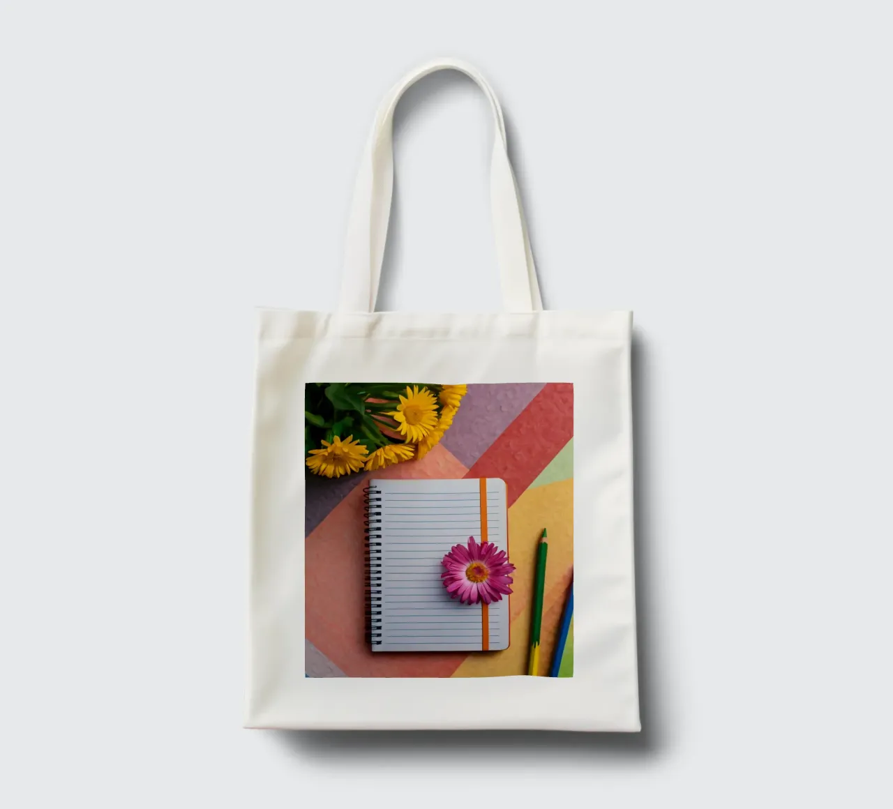 Uno spazio di lavoro colorato con un taccuino con un fiore borsa in juta da DesignDoodle