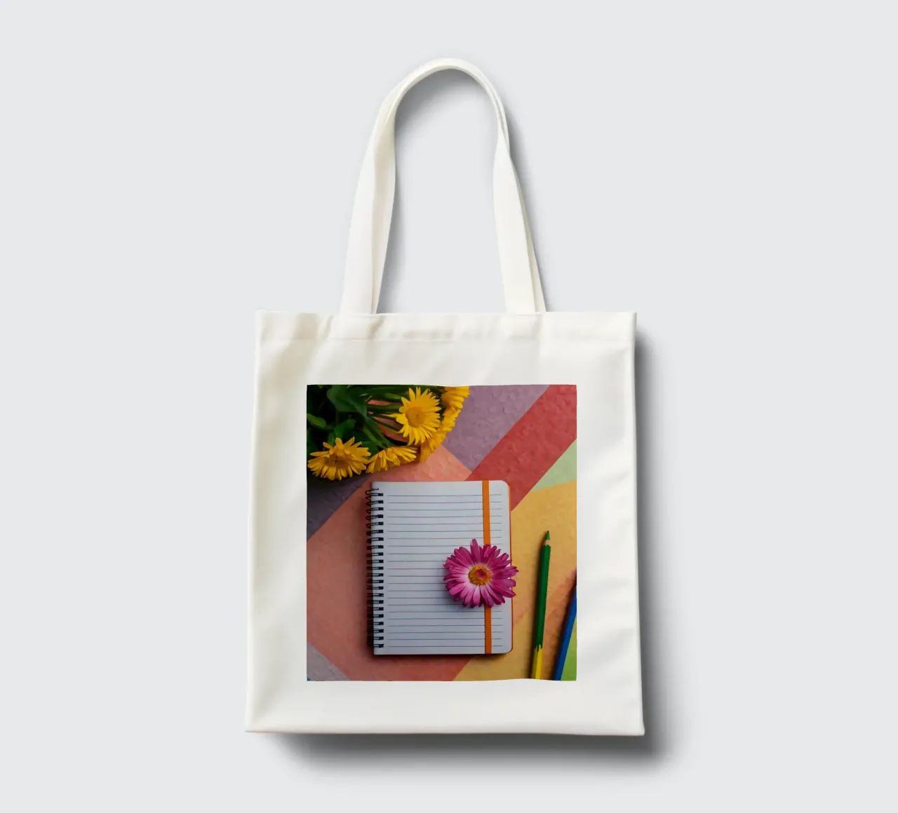 Kleurrijke werkplek met een notitieblok met een bloem jute draagtas van DesignDoodle