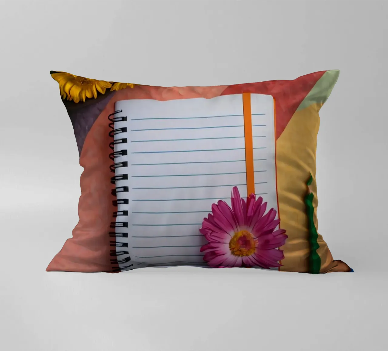 Uno spazio di lavoro colorato con un taccuino con un fiore cuscino da DesignDoodle