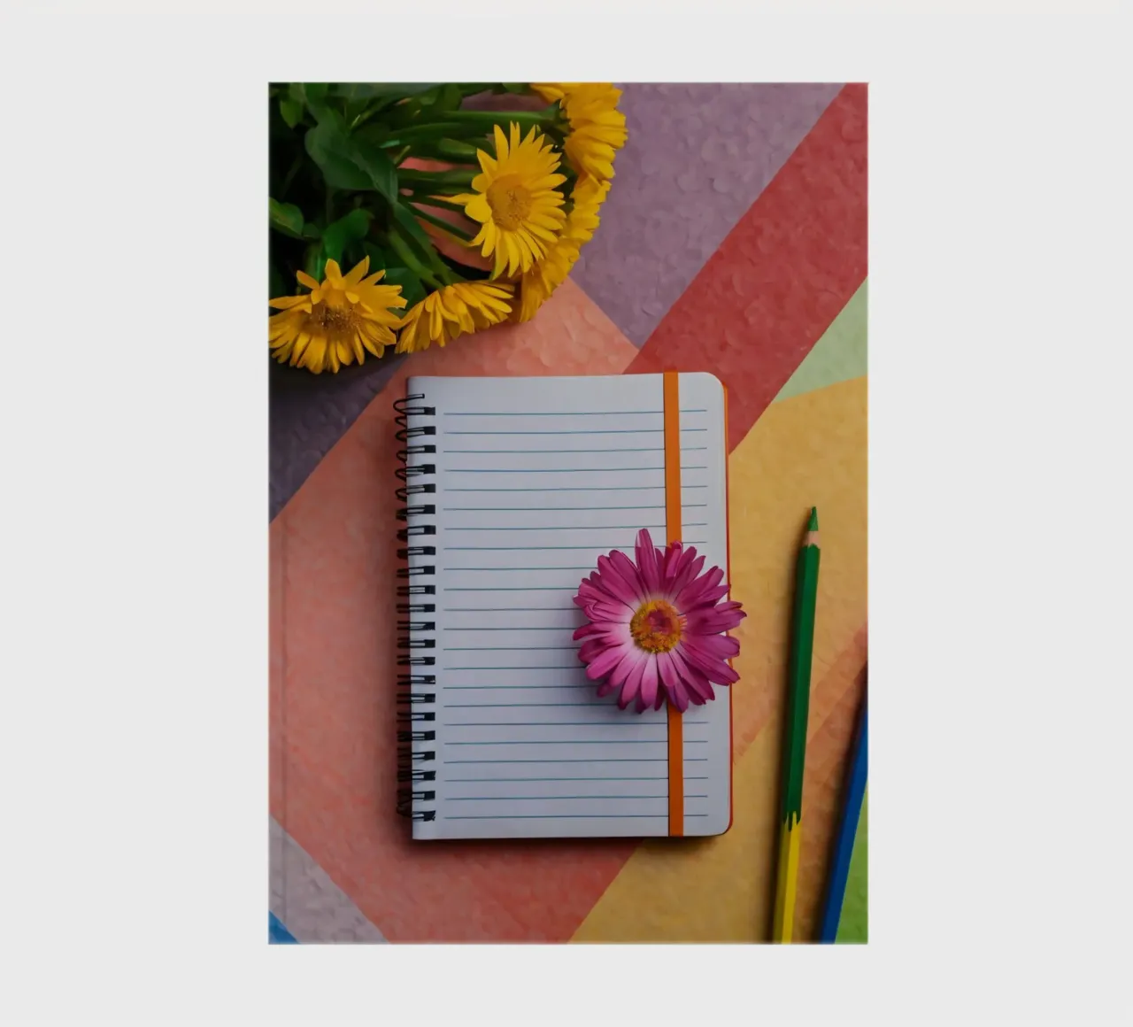 Uno spazio di lavoro colorato con un taccuino con un fiore diario da DesignDoodle