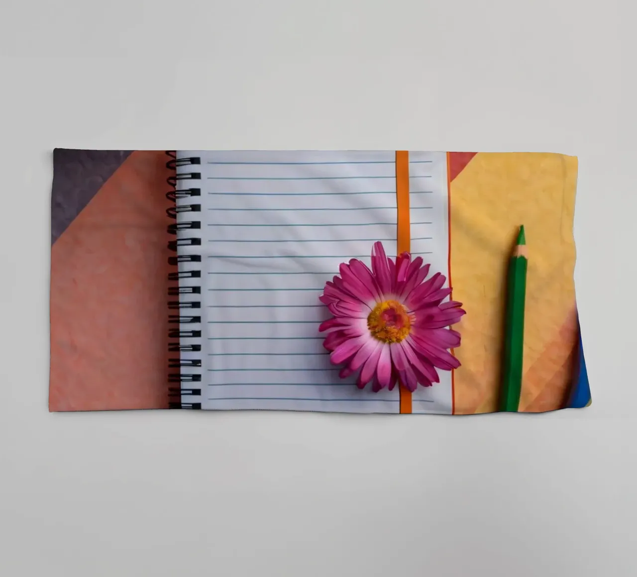 Uno spazio di lavoro colorato con un taccuino con un fiore asciugamano da bagno da DesignDoodle