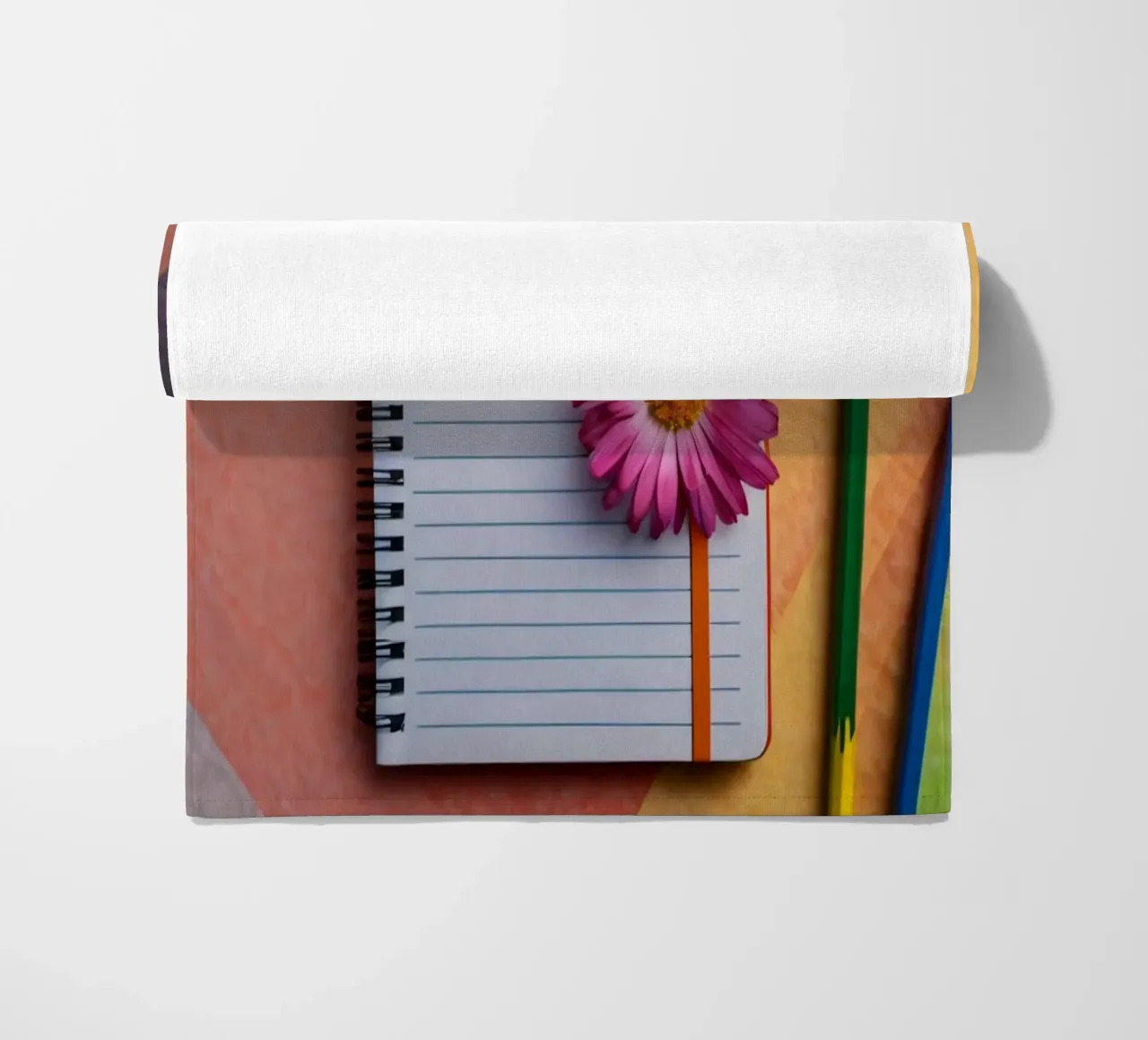 Uno spazio di lavoro colorato con un taccuino con un fiore telo mare da DesignDoodle