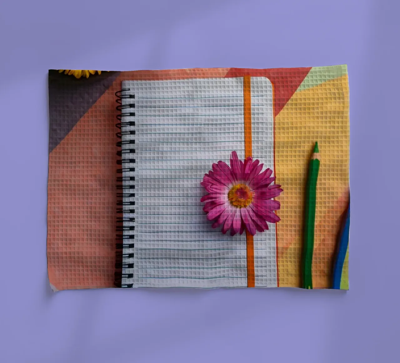 Uno spazio di lavoro colorato con un taccuino con un fiore canovaccio da cucina da DesignDoodle