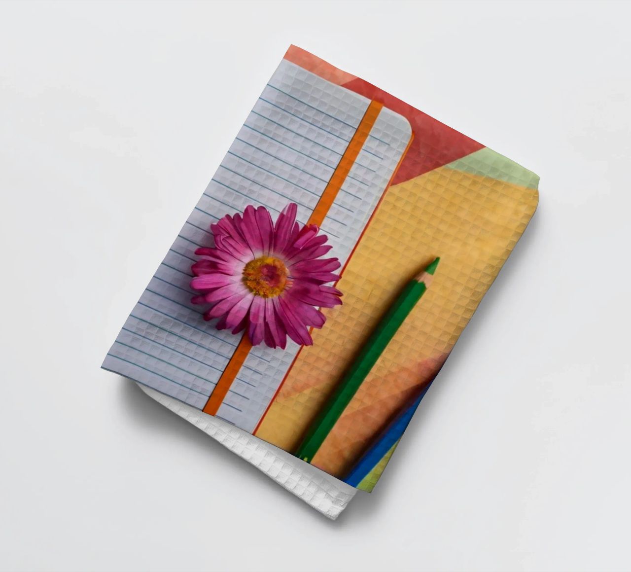 Uno spazio di lavoro colorato con un taccuino con un fiore canovaccio da cucina da DesignDoodle