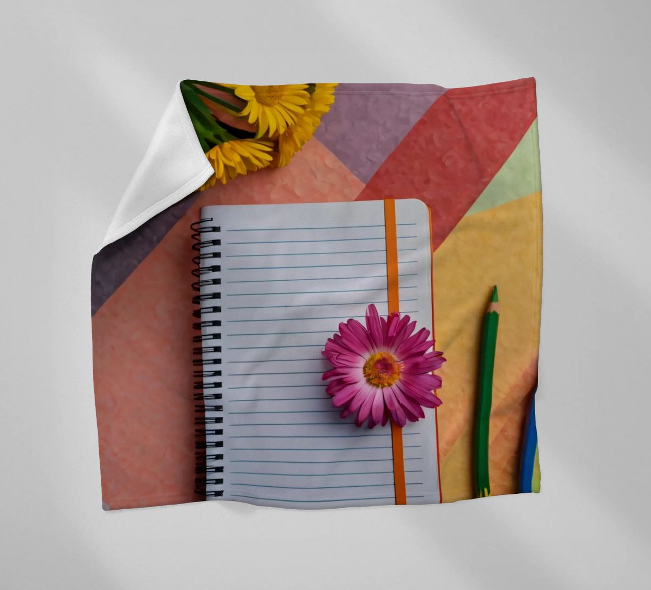 Uno spazio di lavoro colorato con un taccuino con un fiore coperta in pile da DesignDoodle