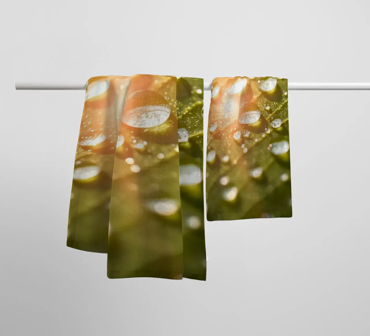 La rugiada mattutina luccica su una foglia verde mentre la luce del sole si infrange asciugamano da bagno da DesignDoodle