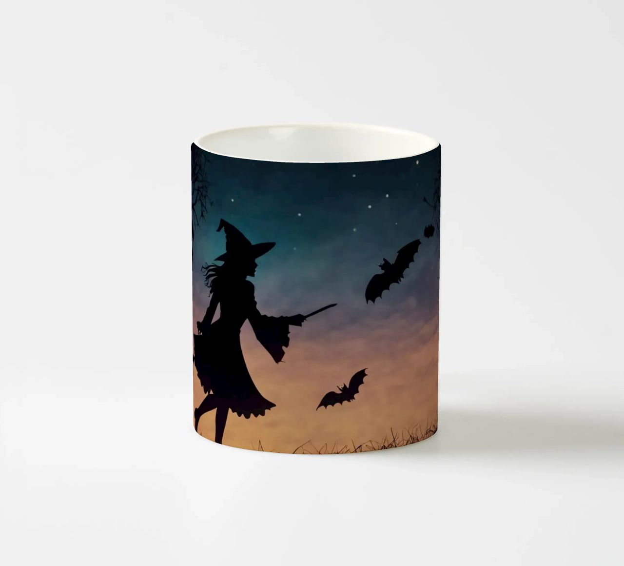 Una strega in controluce che vola su un manico di scopa in un pipistrello crepuscolare tazza in ceramica da DesignDoodle