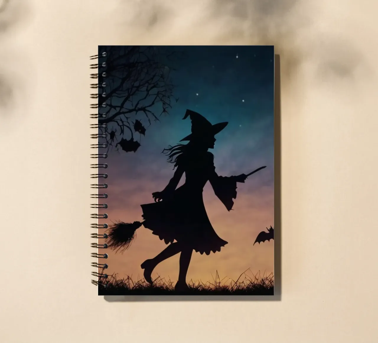Una bruja silueteada volando en escoba en un murciélago crepuscular cuaderno de espiral de DesignDoodle