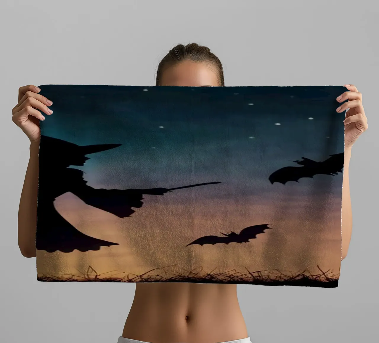 Silhouette d'une sorcière volant sur un balai dans une chauve-souris crépusculaire. serviette de bain de DesignDoodle