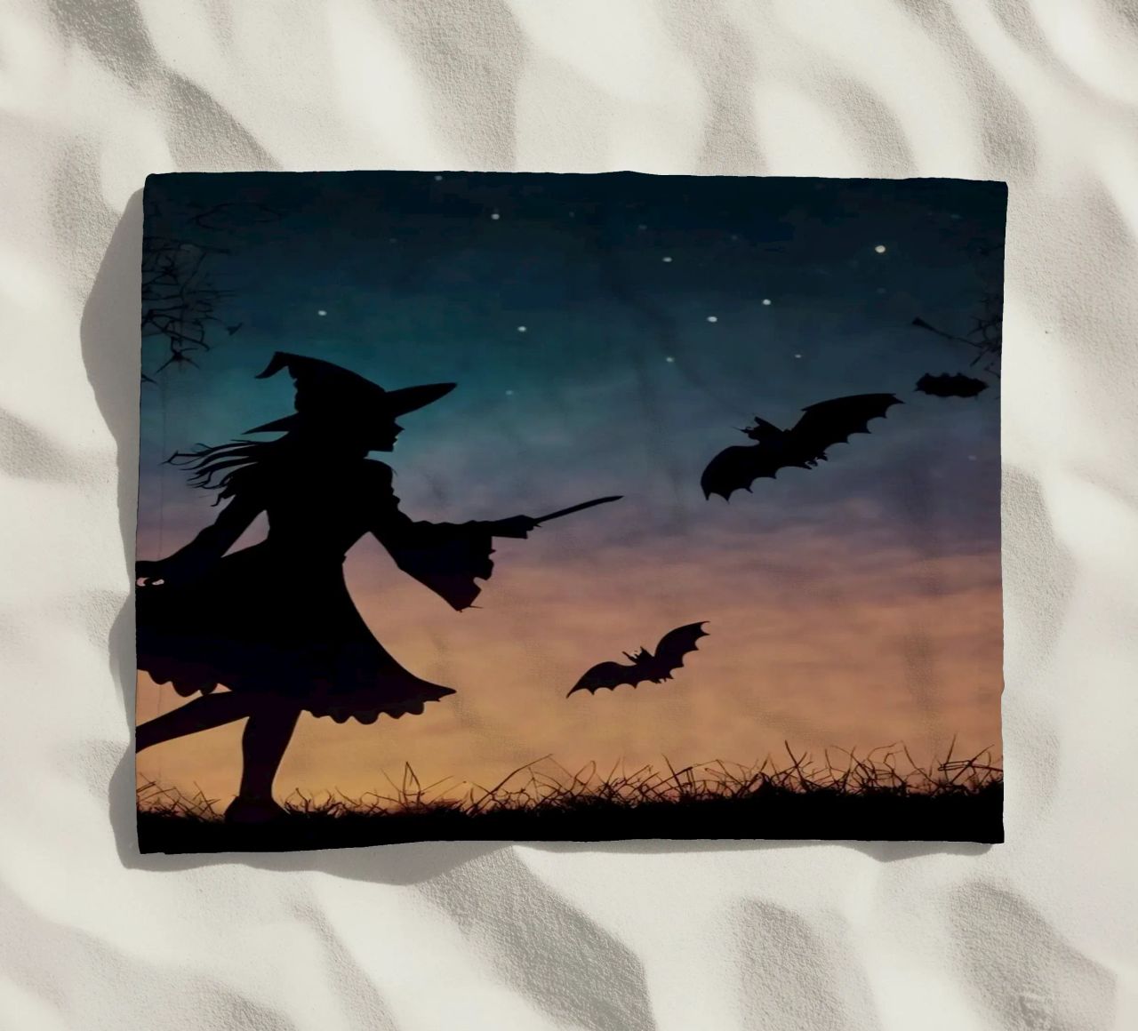 Una strega in controluce che vola su un manico di scopa in un pipistrello crepuscolare telo mare da DesignDoodle