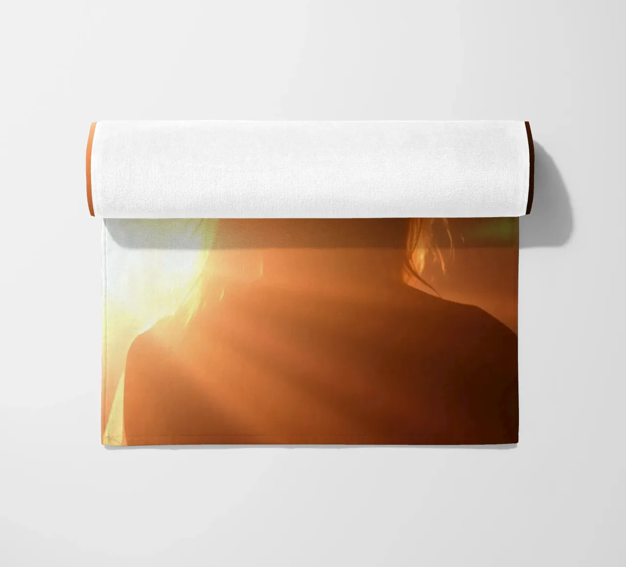 La luce soffusa crea la silhouette di una persona in una calda luminosità telo mare da DesignDoodle