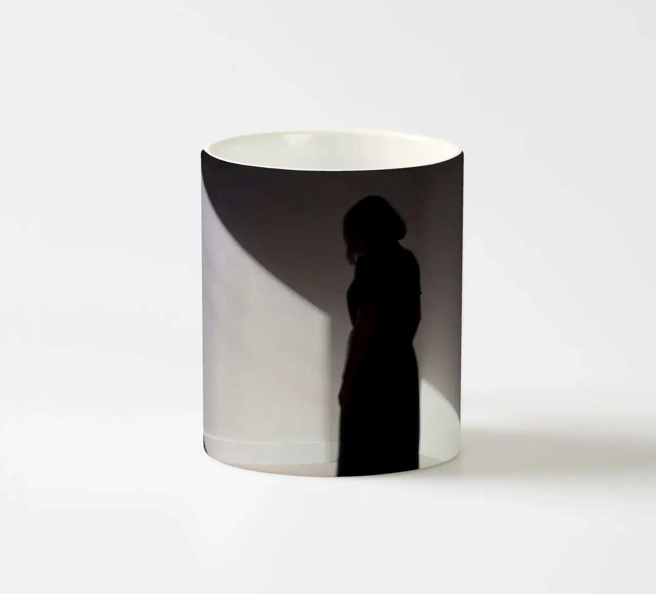 Donna in piedi all'ombra di una luce inquietante tazza in ceramica da DesignDoodle
