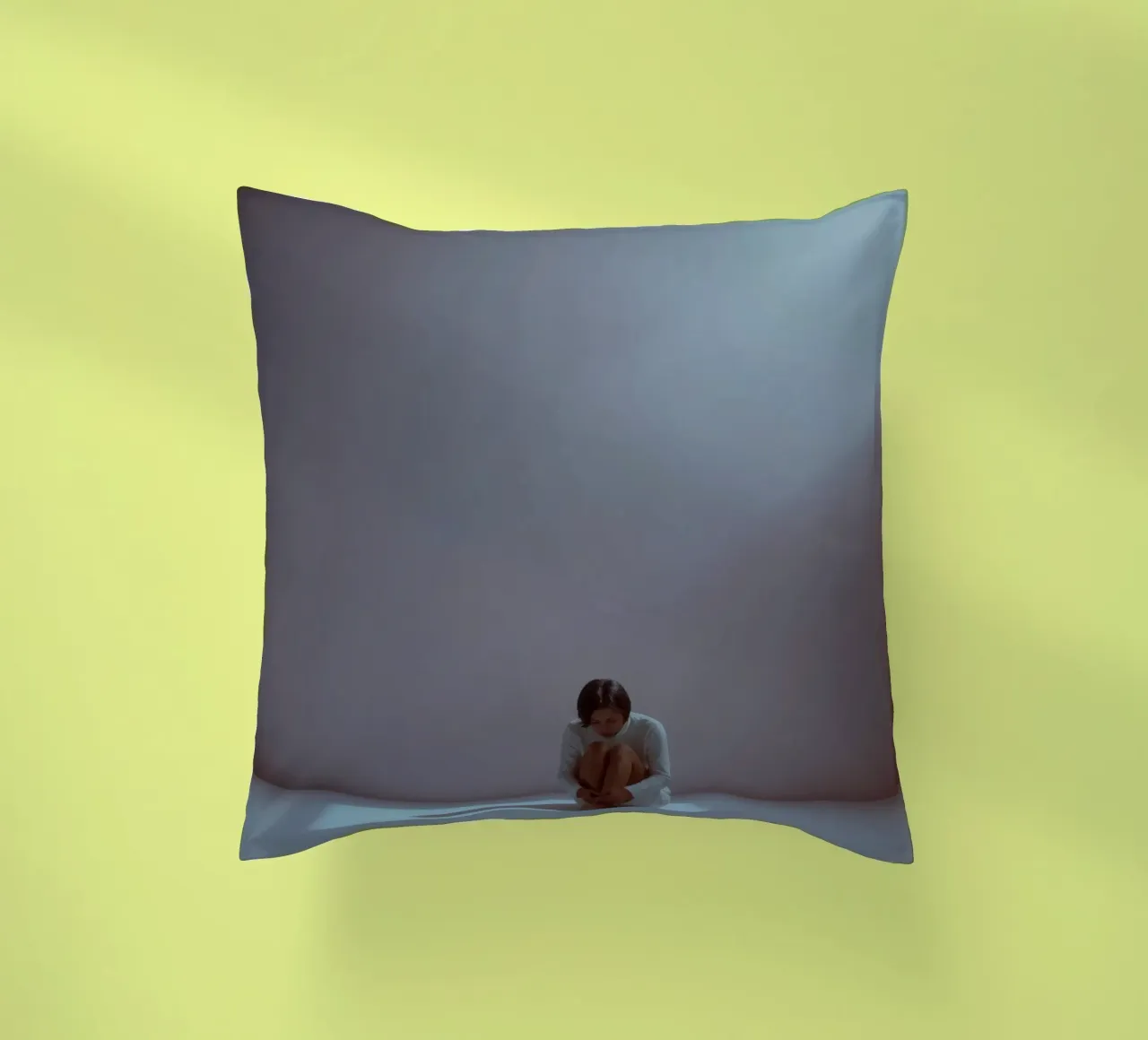 Young woman sits thoughtfully in dimly lit space, reflecting decorative cushion by DesignDoodle