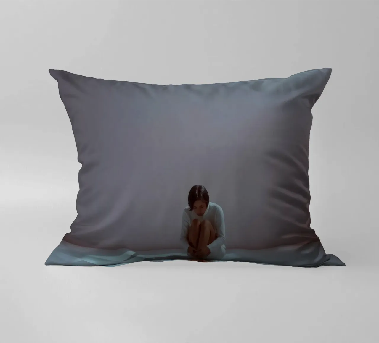 Young woman sits thoughtfully in dimly lit space, reflecting decorative cushion by DesignDoodle