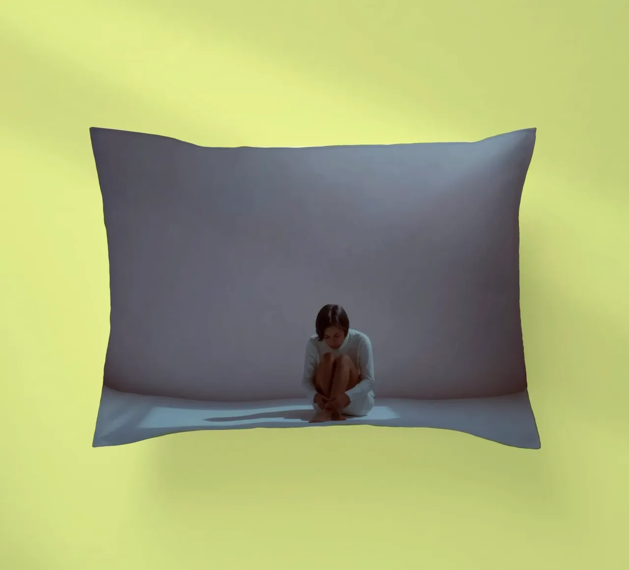 Young woman sits thoughtfully in dimly lit space, reflecting decorative cushion by DesignDoodle