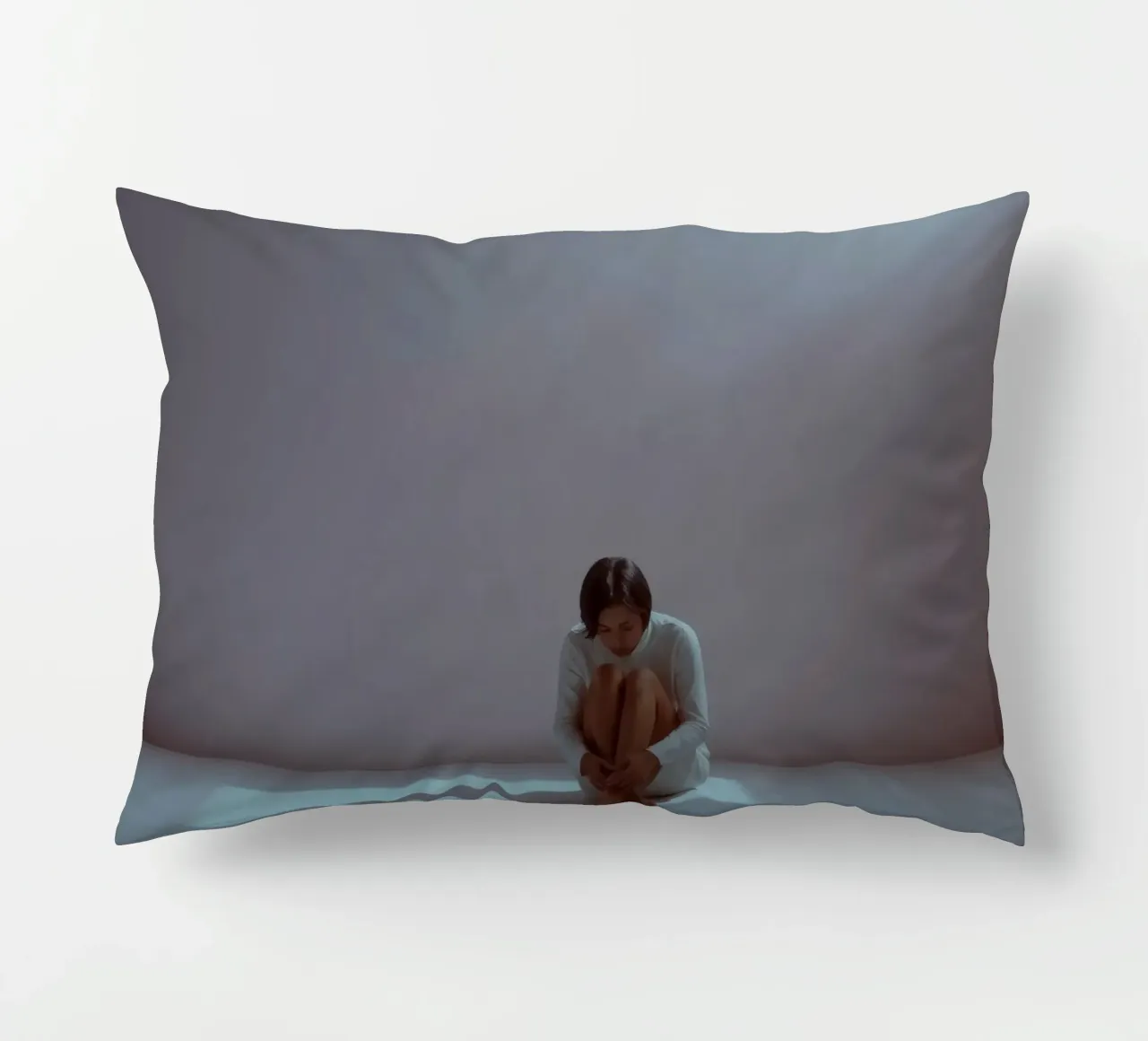 Young woman sits thoughtfully in dimly lit space, reflecting decorative cushion by DesignDoodle