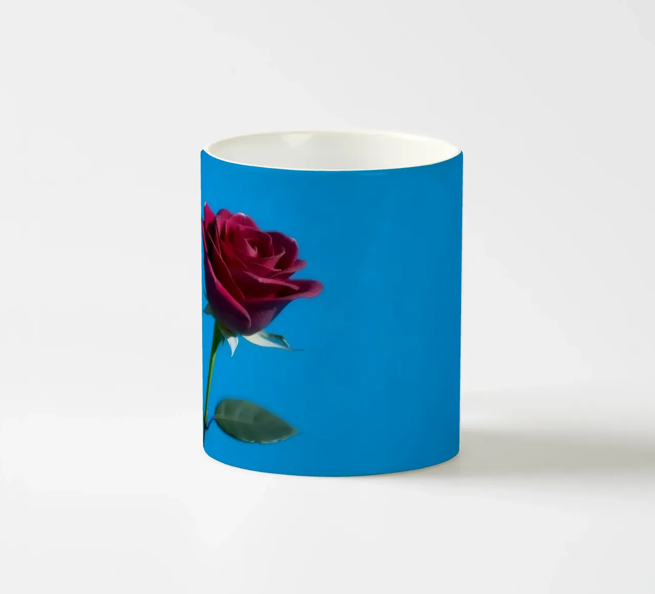 Une rose rouge vif s'épanouit sur un fond bleu vif. mug en céramique de DesignDoodle